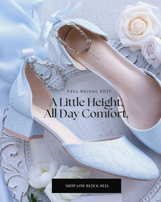 A pair of light blue low block-heel flats with textured fabric and rhinestone ankle straps, styled with white roses on a white tray against a soft blue fabric background. Text overlays read 'FALL BRIDAL EDIT', 'A Little Height, All Day Comfort.